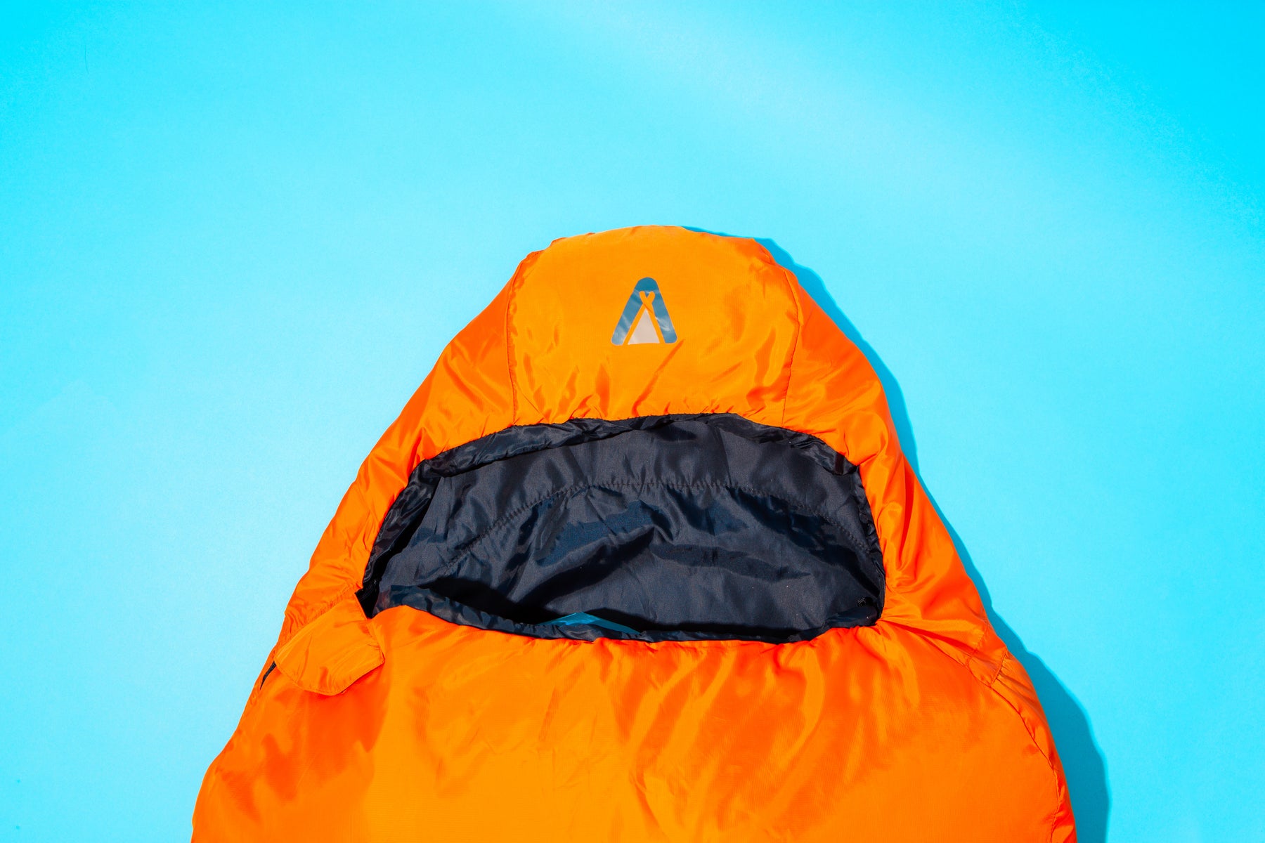 Oranger Mumienschlafsack OFRA 800 von Tambu Outdoor mit offenem Kopfteil auf blauem Hintergrund