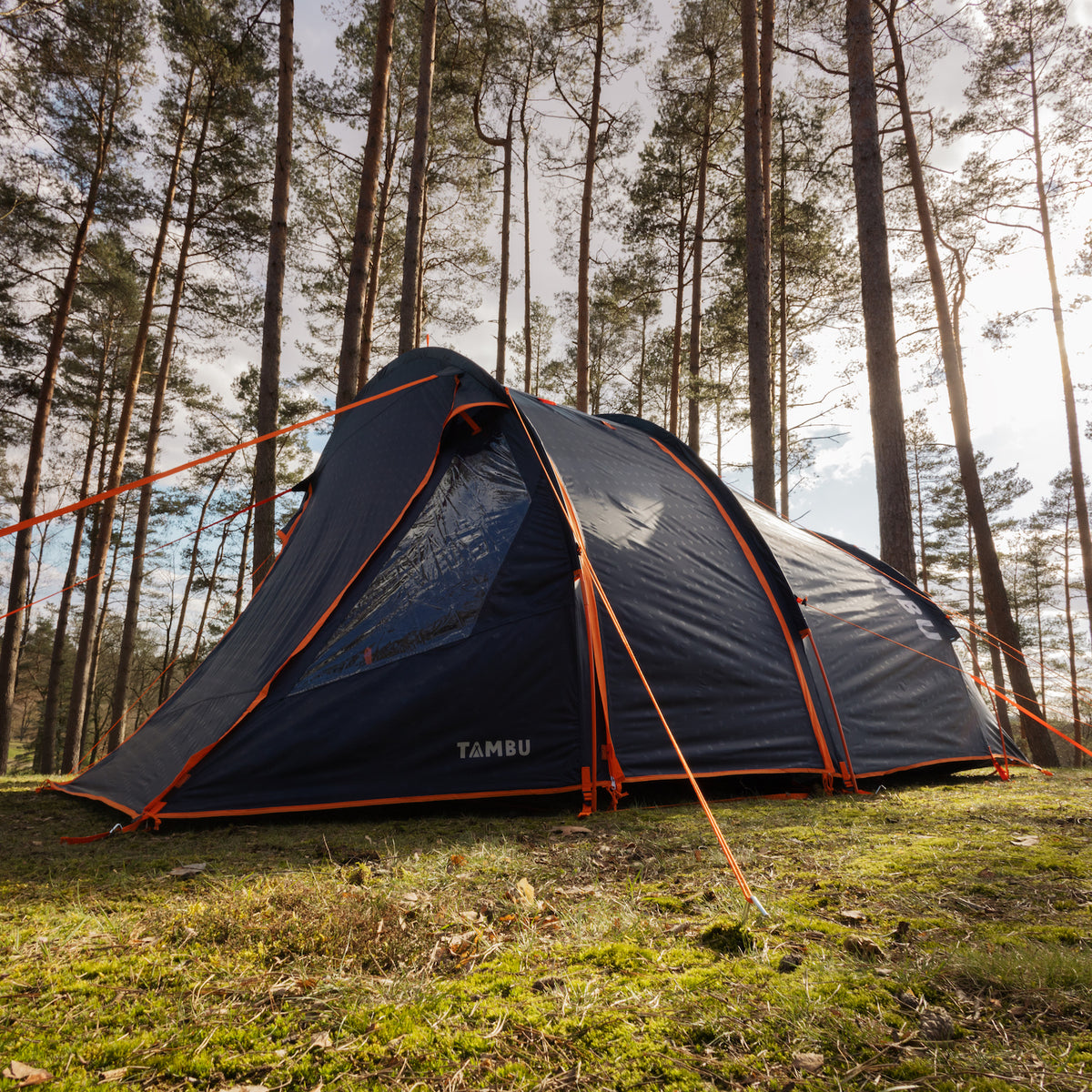 ABAKASA 4 Familien Tunnelzelt von Tambu Outdoor in Blau, aufgestellt im Wald mit orangen Abspannleinen