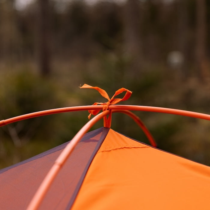 Detailaufnahme der oberen Kreuzung der Gestängebögen in orange des dunkelblauen BESA 3-Personen-Kuppelzelts von Tambu Outdoor