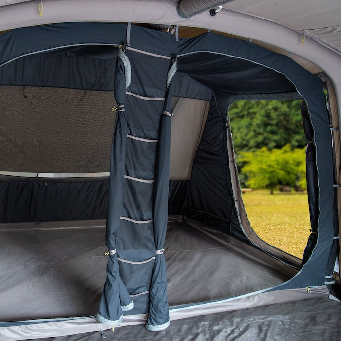 Innenansicht des BISALA 4 Familien Tunnelzelts von Tambu Outdoor mit grauen Wänden und großen Fenstern, Blick auf eine grüne Wiese