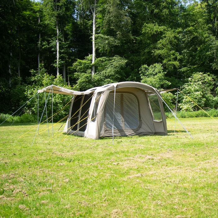 BISALA 4 Familien Tunnelzelt AIR von Tambu Outdoor in Beige auf einer Wiese vor Wald