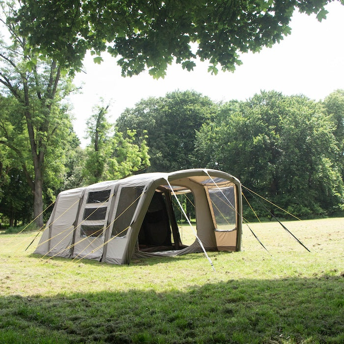 BISALA 5 Familien Tunnelzelt AIR von Tambu Outdoor in Beige, auf einer Wiese mit Bäumen im Hintergrund, mit geöffnetem Eingang und großen Fenstern