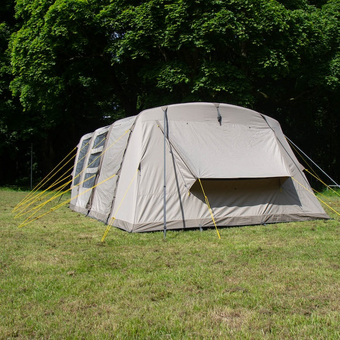 BISALA 5 Familien Tunnelzelt AIR von Tambu Outdoor in Beige, auf einer Wiese vor Bäumen aufgestellt, mit gelben Abspannleinen, Ansicht von Hinten