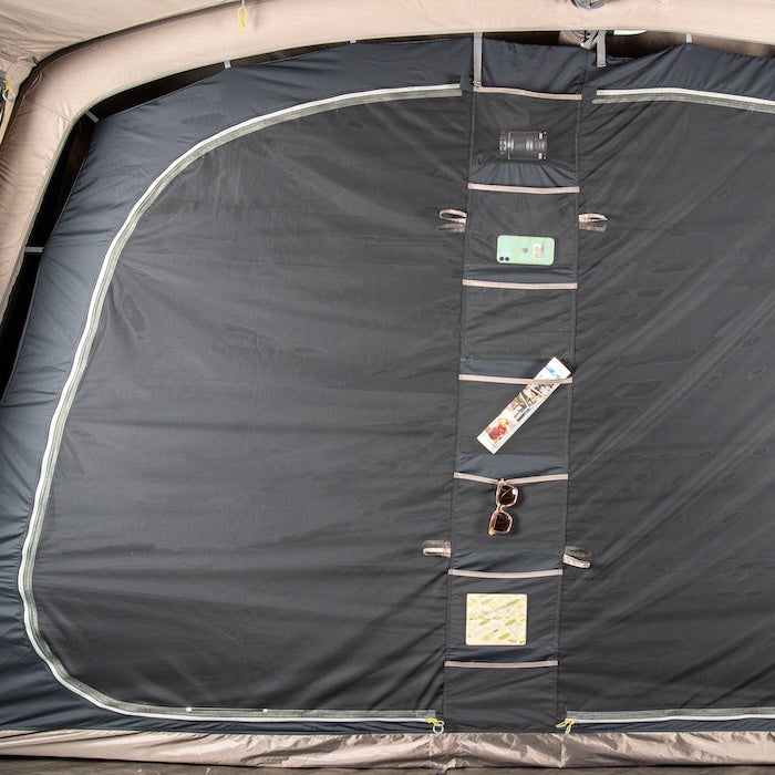 Innenansicht des schwarzen Stauraums mit mehreren Taschen im BISALA 5 Personen Familien Tunnelzelt AIR von Tambu Outdoor, mit Smartphone, Sonnenbrille und Broschüre in den Taschen