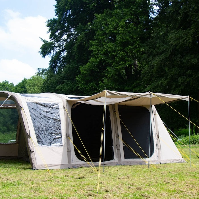 BISALA 5 Familien Tunnelzelt AIR von Tambu Outdoor in Beige mit zwei großen Eingängen und Vordach auf einer Wiese vor Bäumen