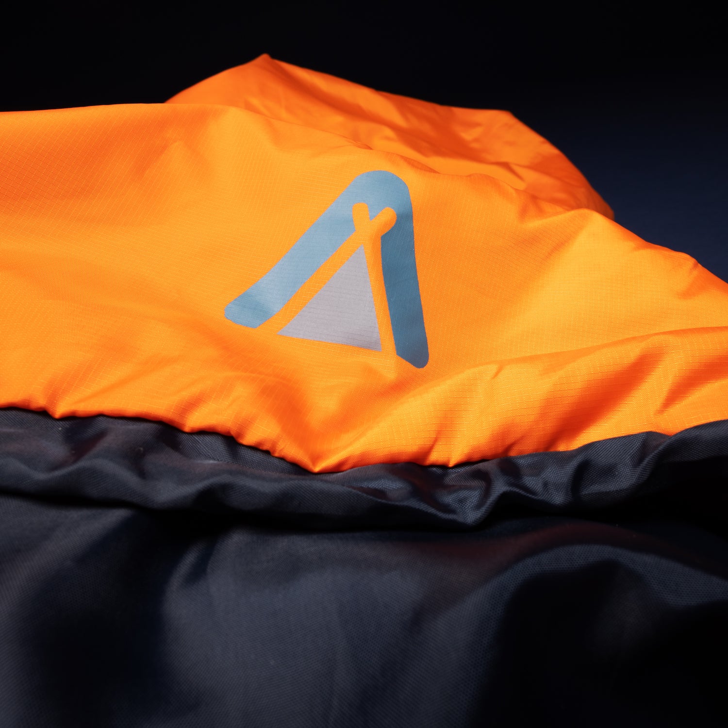 Nahaufnahme des orange-schwarzen HASA 950 Deckenschlafsacks von Tambu Outdoor mit sichtbarem Logo