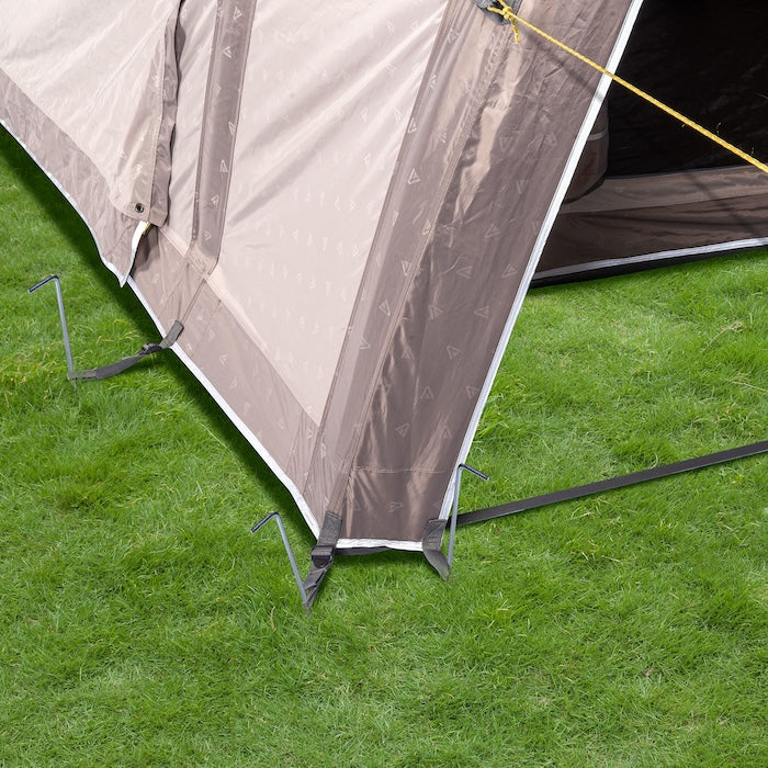 Ecke des BISALA VAN Busvorzelts AIR von Tambu Outdoor mit beige-braunem Stoff, befestigt mit Heringen und Spannseilen auf grünem Gras