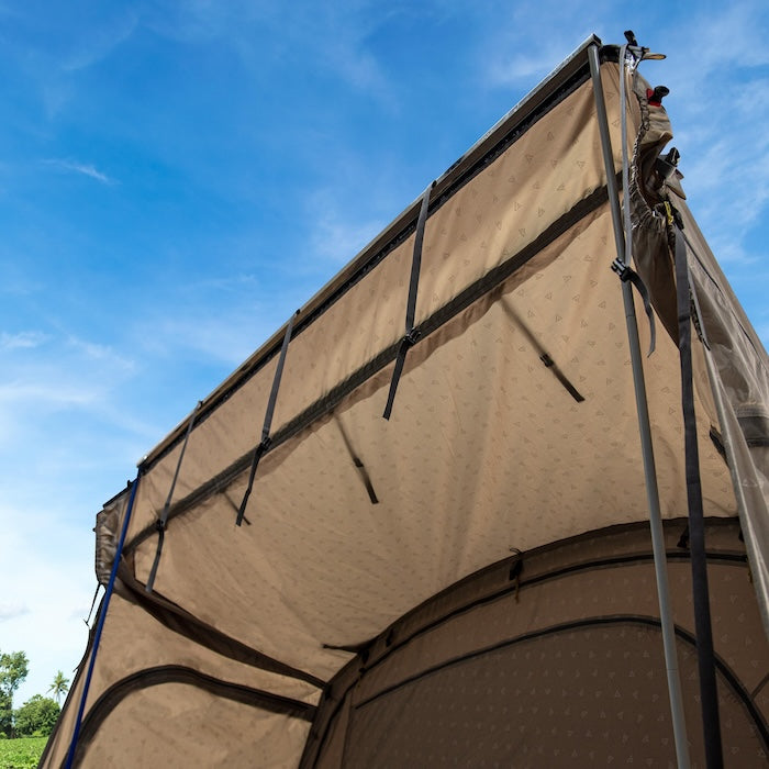 BISALA VAN Busvorzelt AIR von Tambu Outdoor, beige Vorzelt mit aufgespannter Schleuse und Befestigungsriemen vor blauem Himmel