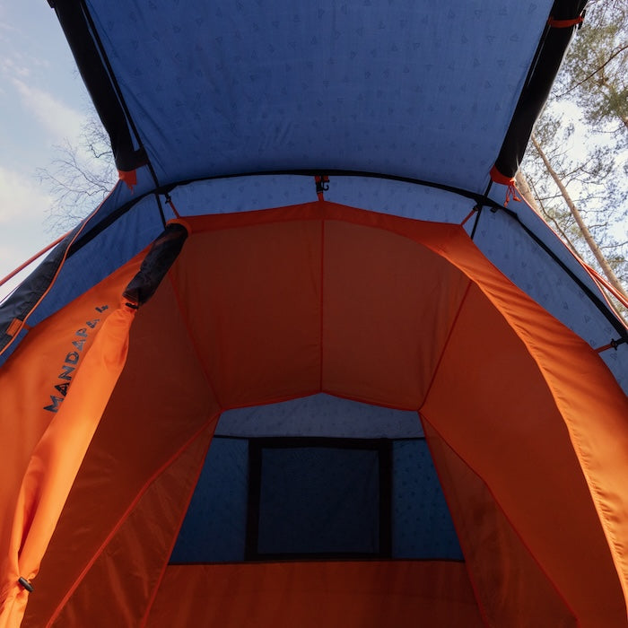 Innenansicht des blauen MANDAPA 4 Familienzelts von Tambu Outdoor mit orangefarbenem Eingang und Fenster im Hintergrund