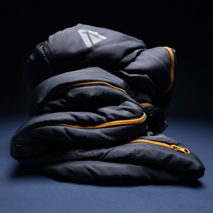 Gefalteter NEEL 750 Mumienschlafsack von Tambu Outdoor in dunklem Blau blauem Untergrund
