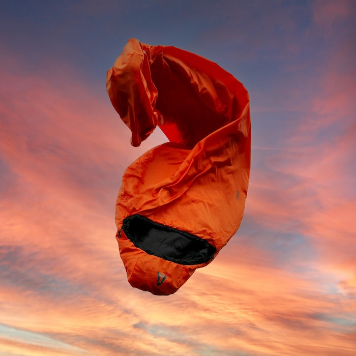 Oranger Mumienschlafsack OFRA 800 von Tambu Outdoor vor einem farbigen Sonnenuntergangshimmel