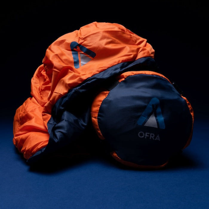 OFRA 800 Mumienschlafsack von Tambu Outdoor in Orange und Dunkelblau, teilweise zusammengerollt mit sichtbarem OFRA-Logo
