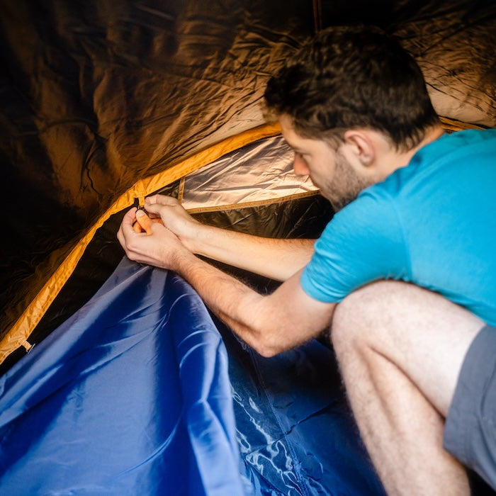 Mann befestigt Innenzelt im SURANGA 2.0 Leichtgewichts-Trekkingzelt von Tambu Outdoor, blaues Innenzelt, gelbfarbene Zeltkante