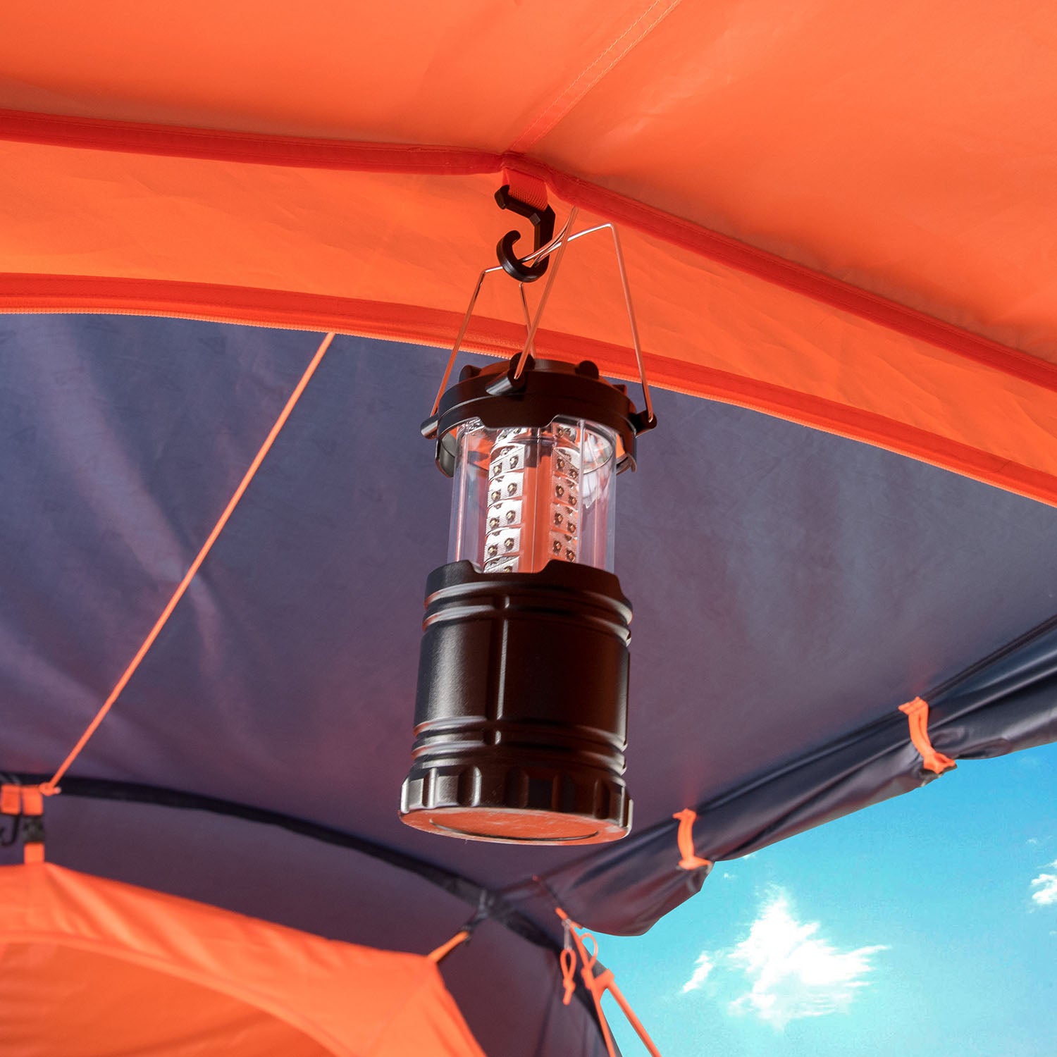 Schwarze LED-Campinglaterne hängt im Inneren eines blauen MANDAPA 4 Familienzelts von Tambu Outdoor