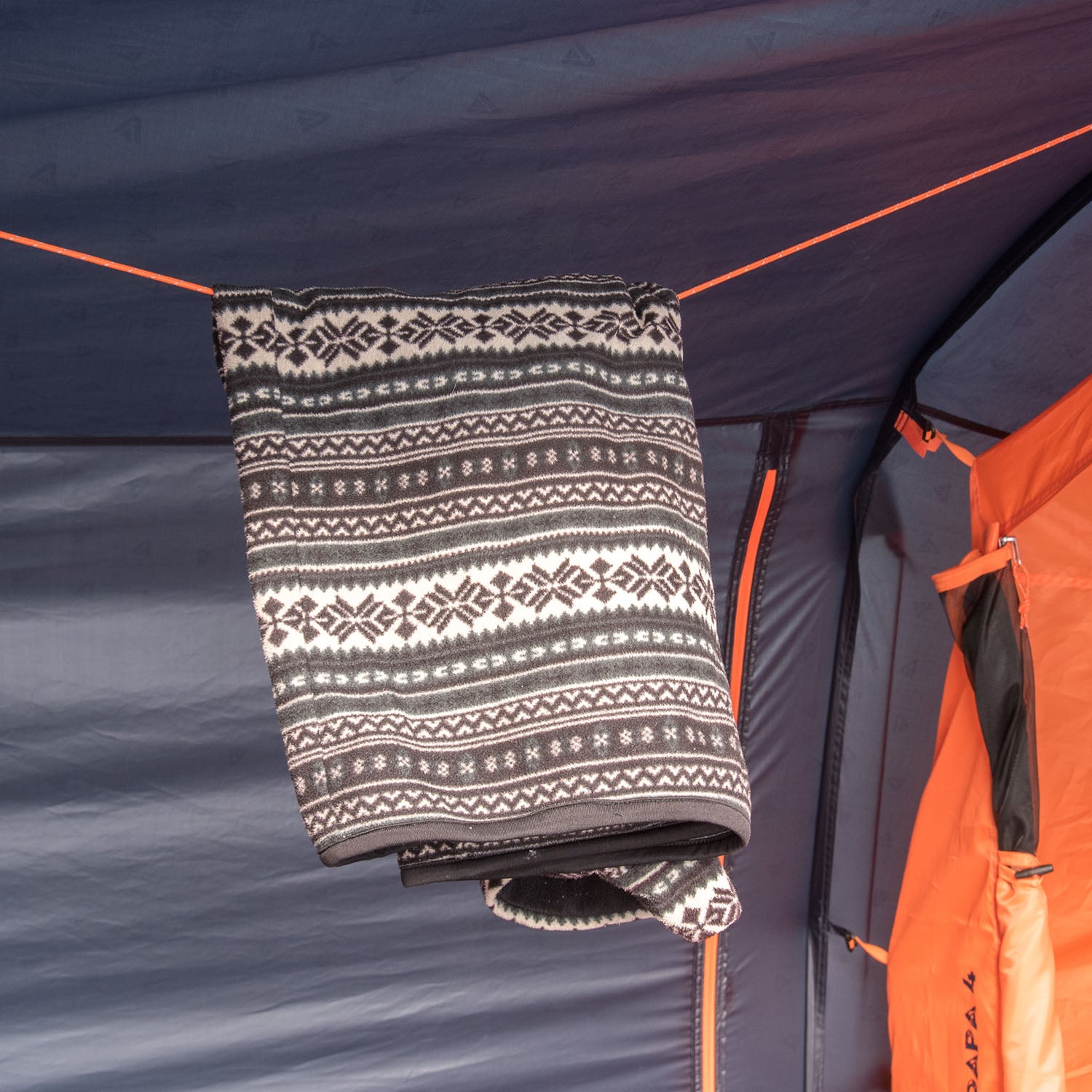Innenansicht des blauen Mandapa 4 Familienzelts von Tambu Outdoor mit einer schwarz-weißen Decke mit Norwegermuster, aufgehängt an einer Schnur