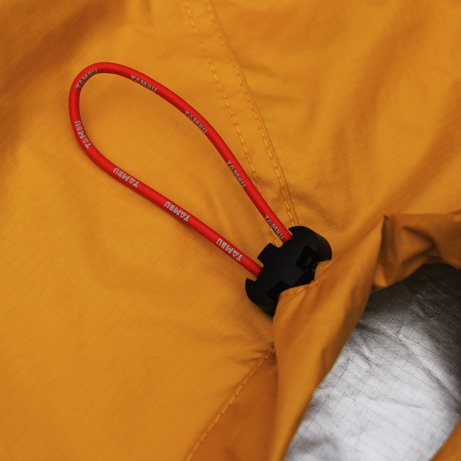 Nahaufnahme eines roten Kordelzugs mit schwarzem Stopper an einem gelbfarbenen Biwacksack MARI 350 von Tambu Outdoor